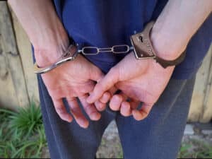 Man handcuffed with hands behind back outdoors.