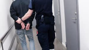 Prison guard esicort inmate throught corridor in jail corridor for booking after arrest.